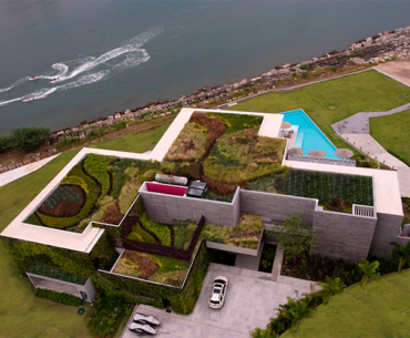 Casa à beira-mar destaca-se por sua cobertura verde